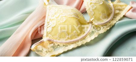 Delicate Yellow Lace Lingerie with Pink Trim Details on Soft Pastel Silk Background 122859071