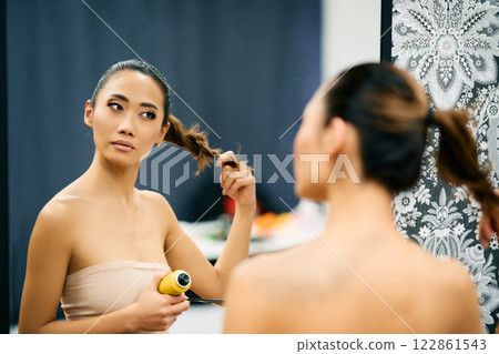 Beautiful asian woman fixing her hair looking in mirror. Beautiful asian woman fixing her hair looking in mirror. 122861543