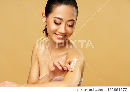 Young beautiful woman applying moisturizing cream on her body 122861577
