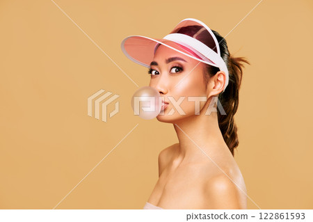 Trendy young woman blowing bubble gum on beige background. 122861593