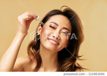 Happy smiling woman applying facial serum using pipette dropper. Moisturising and nourishing. Happy smiling woman applying facial serum using pipette dropper. Moisturising and nourishing. 122861600