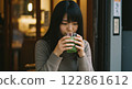 A woman drinking a drink while looking down in a cafe 122861612