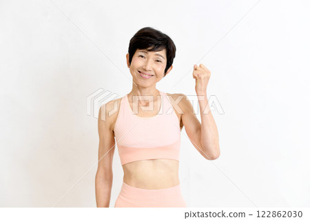 Middle-aged woman in gym wear posing with fist Middle-aged woman in gym wear posing with fist 122862030
