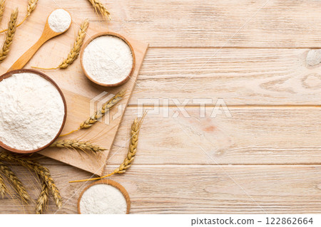 Flat lay of Wheat flour in wooden bowl with wheat spikelets on colored background. world wheat crisis 122862664