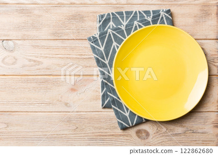 Top view on colored background empty round yellow plate on tablecloth for food. Empty dish on napkin with space for your design Top view on colored background empty round yellow plate on tablecloth for food. Empty dish on napkin with space for your design 122862680