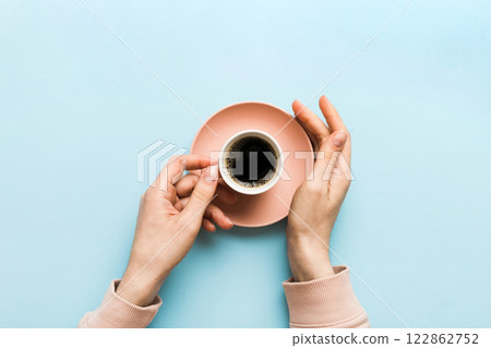 Minimalistic style woman hand holding a cup of coffee on Colored background. Flat lay, top view cappuccino cup. Empty place for text, copy space. Coffee addiction. Top view, flat lay 122862752