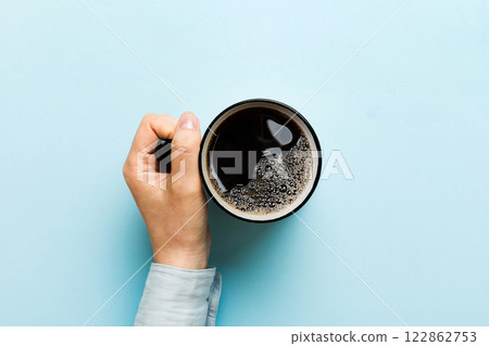 Minimalistic style woman hand holding a cup of coffee on Colored background. Flat lay, top view cappuccino cup. Empty place for text, copy space. Coffee addiction. Top view, flat lay 122862753
