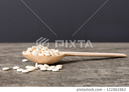 Heap of white pills on colored background. Tablets scattered on a table. Pile of red soft gelatin capsule. Vitamins and dietary supplements concept Heap of white pills on colored background. Tablets scattered on a table. Pile of red soft gelatin capsule. Vitamins and dietary supplements concept 122862862