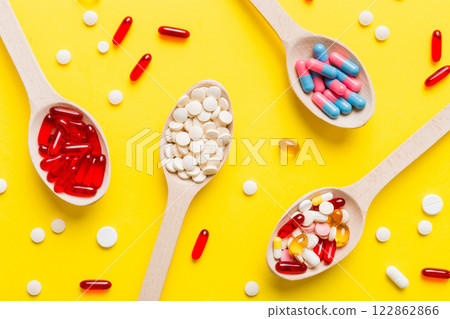 Vitamin capsules in a spoon on a colored background. Pills served as a healthy meal. Red soft gel vitamin supplement capsules on spoon Vitamin capsules in a spoon on a colored background. Pills served as a healthy meal. Red soft gel vitamin supplement capsules on spoon 122862866