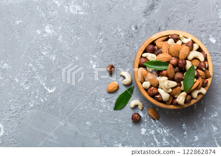 Assortment of nuts in wooden bowl on colored table. Cashew, hazelnuts, walnuts, almonds. Mix of nuts Top view with copy space Assortment of nuts in wooden bowl on colored table. Cashew, hazelnuts, walnuts, almonds. Mix of nuts Top view with copy space 122862874