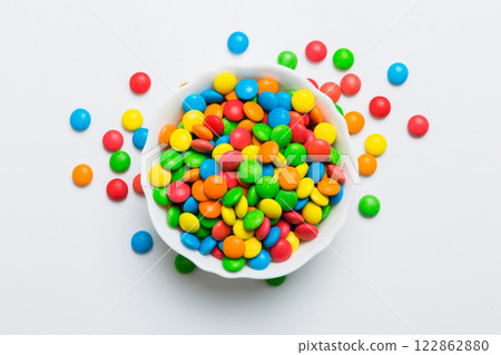 Multicolored candies in a bowl on a colored background. birthday and holiday concept. Top view with copy space 122862880