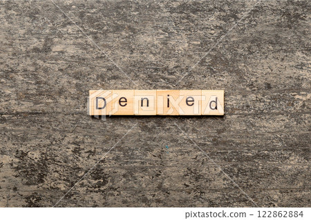 DENIED word written on wood block. DENIED text on cement table for your desing, concept 122862884