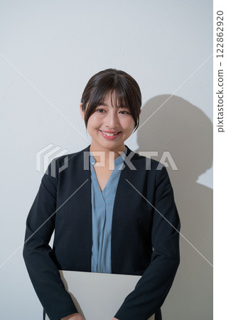 A smiling Japanese woman holding a laptop on a white background 122862920