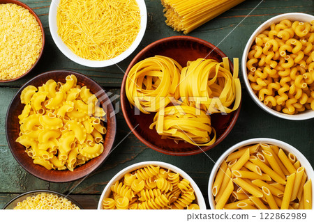 Assorted Uncooked Pasta in Bowls on Wooden Table 122862989