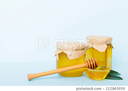 Honey in jar with leaves and honey dipper on colored background top view with copy text Honey in jar with leaves and honey dipper on colored background top view with copy text 122863050