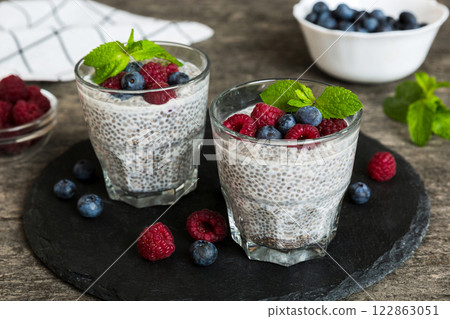 Healthy breakfast or morning with chia seeds vanilla pudding raspberry and blueberry berries on table background, vegetarian food, diet and health concept. Chia pudding with raspberry and blueberry 122863051