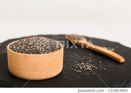Chia seeds in bowl and spoon on colored background. Healthy Salvia hispanica in small bowl. Healthy superfood Chia seeds in bowl and spoon on colored background. Healthy Salvia hispanica in small bowl. Healthy superfood 122863065
