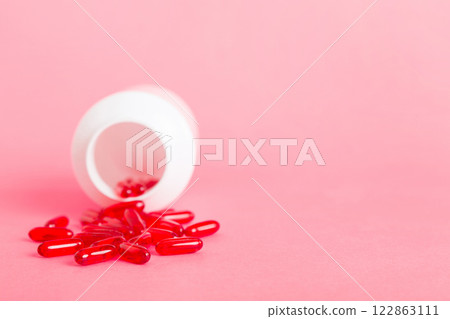 Red pills spilled around a pill bottle. Medicines and prescription pills flat lay background. Red medical capsules Red pills spilled around a pill bottle. Medicines and prescription pills flat lay background. Red medical capsules 122863111
