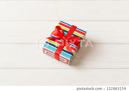 Wrapped christmas or other holiday handmade present in paper with colored ribbon. Present box, decoration of gift on table, top view with copy space 122863159