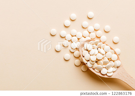 Heap of white pills on colored background. Tablets scattered on a table. Pile of red soft gelatin capsule. Vitamins and dietary supplements concept 122863176