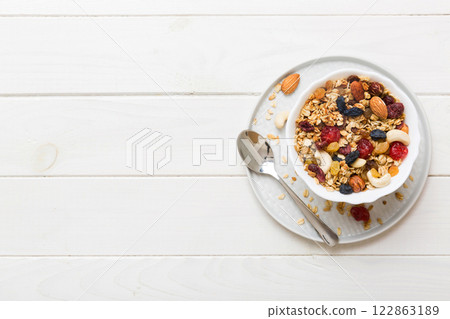 Cooking a wholesome breakfast. Granola with Various dried fruits and nuts in a bowl. The concept of a healthy dessert. Flat lay, top view with copy space Cooking a wholesome breakfast. Granola with Various dried fruits and nuts in a bowl. The concept of a healthy dessert. Flat lay, top view with copy space 122863189