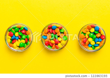 Multicolored candies in a bowl on a colored background. birthday and holiday concept. Top view with copy space 122863193
