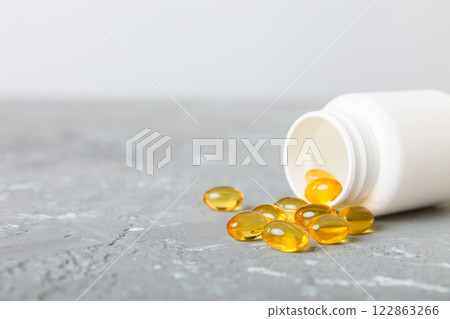 Soft gels pills with Omega-3 oil spilling out of pill bottle close-up. Gel capsules bottle white surface. Omega 3, multivitamins, Calcium, antibiotics. Health. Immunity 122863266
