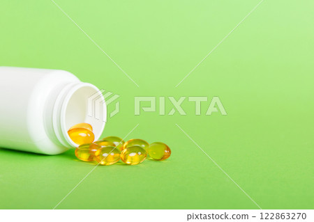 Soft gels pills with Omega-3 oil spilling out of pill bottle close-up. Gel capsules bottle white surface. Omega 3, multivitamins, Calcium, antibiotics. Health. Immunity Soft gels pills with Omega-3 oil spilling out of pill bottle close-up. Gel capsules bottle white surface. Omega 3, multivitamins, Calcium, antibiotics. Health. Immunity 122863270