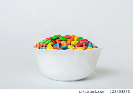Multicolored candies in a bowl on a colored background. birthday and holiday concept. Top view with copy space Multicolored candies in a bowl on a colored background. birthday and holiday concept. Top view with copy space 122863278