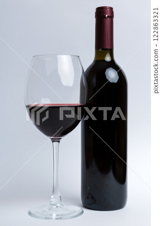 Glass of red wine and a bottle on colored table. Flat lay, top view wth copy space 122863321