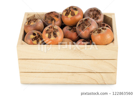 Brown fresh medlars in wooden box isolated on white background. Mespilus germanica close-up Brown fresh medlars in wooden box isolated on white background. Mespilus germanica close-up 122863560