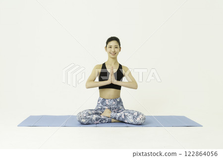 白色背景下,微笑著盤腿唱歌的年輕女子 白色背景下,微笑著盤腿唱歌的年輕女子 122864056