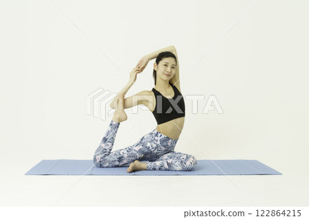 白色背景下做鴿子式瑜珈的年輕女子 122864215