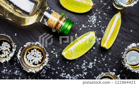 Tequila shot setup complete with lime slices and salt positioned on a dark background 122864421