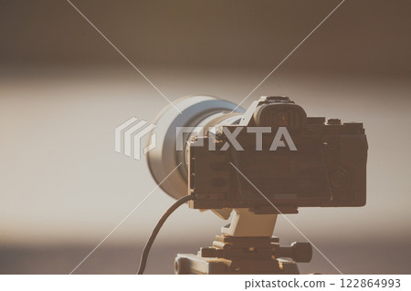 Camera DSLR set on tripod capturing sunset on beach. Camera DSLR set on tripod capturing sunset on beach. 122864993
