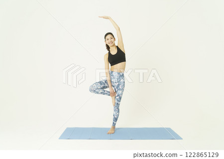 Young woman doing yoga pose on white background stretching Young woman doing yoga pose on white background stretching 122865129