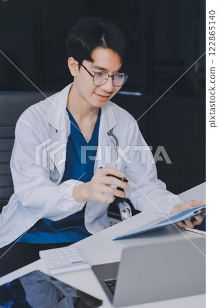 Positive doctor working on laptop in medical office, portrait. Positive doctor working on laptop in medical office, portrait. 122865140