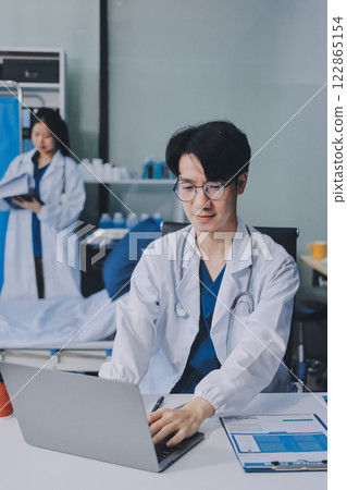 Positive doctor working on laptop in medical office, portrait. Positive doctor working on laptop in medical office, portrait. 122865154