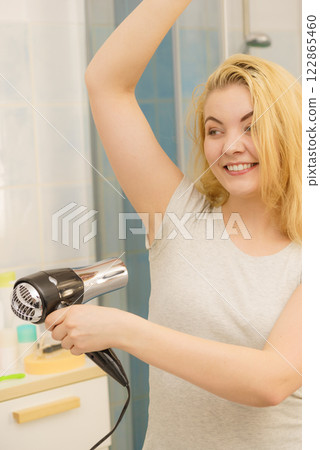 Woman drying sweat stains using hair dryer 122865460