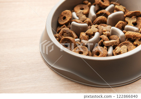 Dry dog food in a slow feeder bowl placed on a wooden surface Dry dog food in a slow feeder bowl placed on a wooden surface 122866840