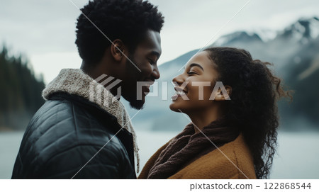 Happy black American young couple together outdoors against a snowy mountain landscape background 122868544
