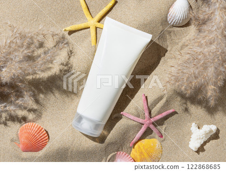 Sunscreen cream tube, starfishes and seashells on a sand top view, hand shadow, cosmetic mockup Sunscreen cream tube, starfishes and seashells on a sand top view, hand shadow, cosmetic mockup 122868685