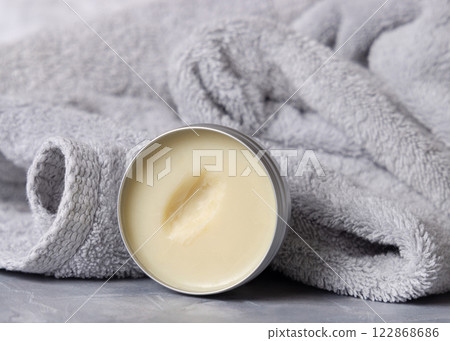Opened body butter jar near light grey bath towel close up, cosmetic mockup 122868686