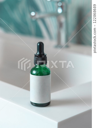 Green glass dropper bottle with pipette on washbasin in green bathroom close up cosmetic mockup 122868689