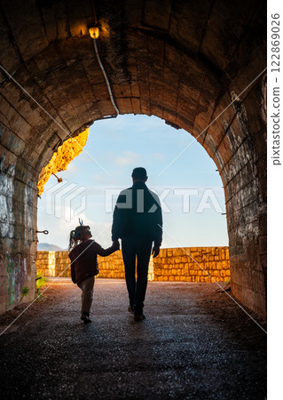 Father and daughter in pedestrian tunnel through a rock or mountain near Petrovac town in winter time, Montenegro Father and daughter in pedestrian tunnel through a rock or mountain near Petrovac town in winter time, Montenegro 122869026