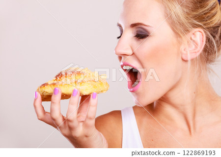 undecided woman holds cake sweet bun in hand undecided woman holds cake sweet bun in hand 122869193