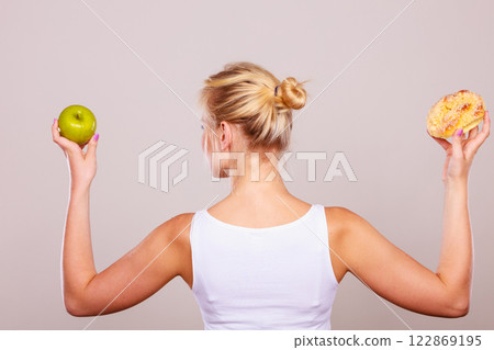 Woman holds cake and fruit in hand choosing Woman holds cake and fruit in hand choosing 122869195