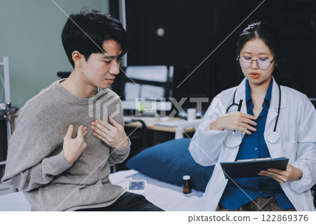 Female physician reads medical history while visiting her patient Female physician reads medical history while visiting her patient 122869376