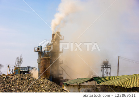 white steam rising up from pipe of small asphalt factory at day time with piles of gravel in a foreground white steam rising up from pipe of small asphalt factory at day time with piles of gravel in a foreground 122869511