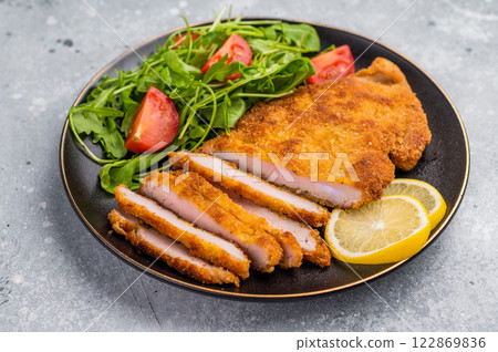 Fried Weiner schnitzel steak, veal breaded meat with salad on a plate. grey background. top view 122869836